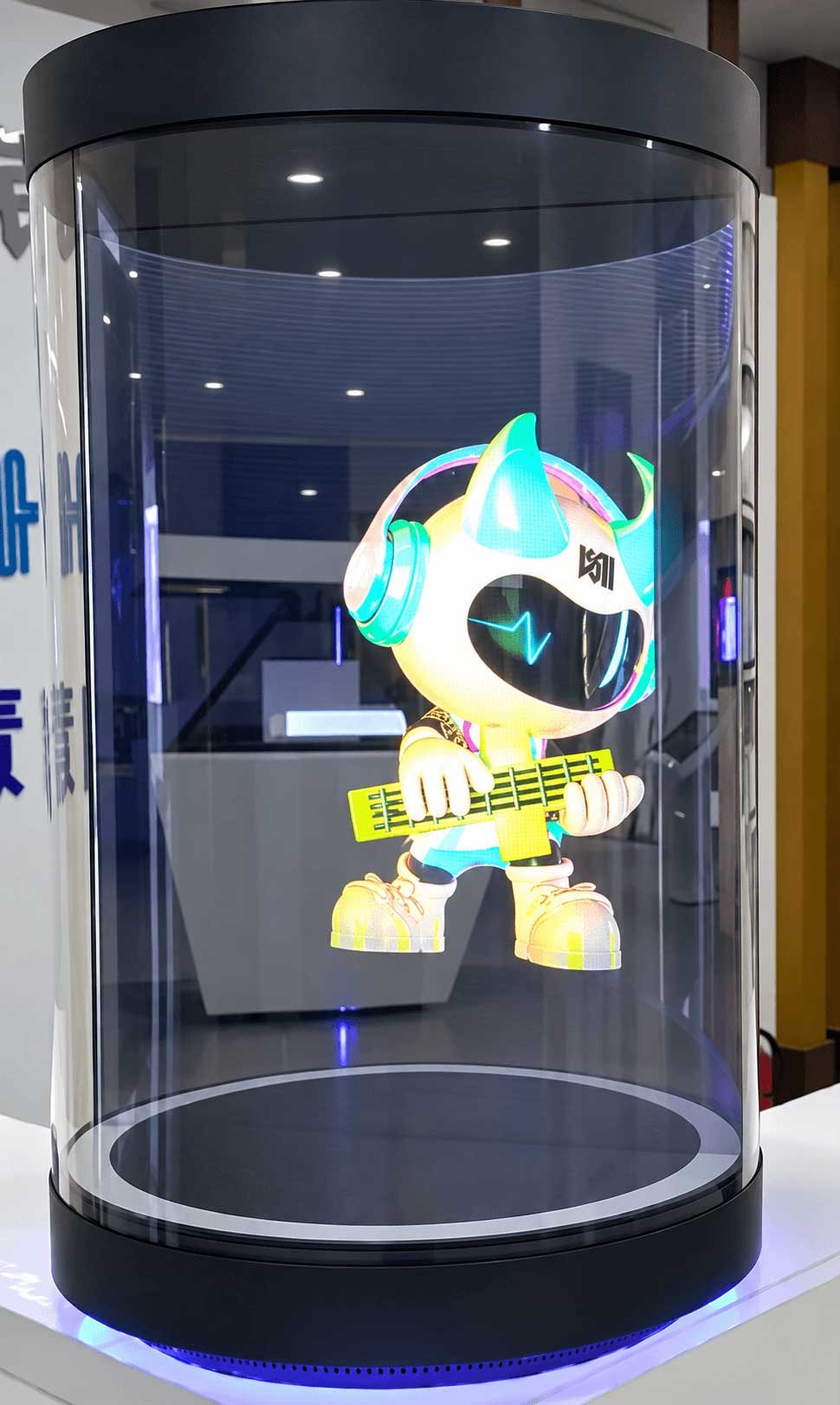 Illustrative 21.5-inch holographic cylinder display with an animated mascot