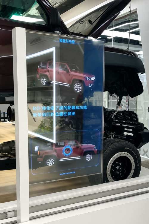 Transparent OLED sliding-rail display moving in front of an automotive exhibit